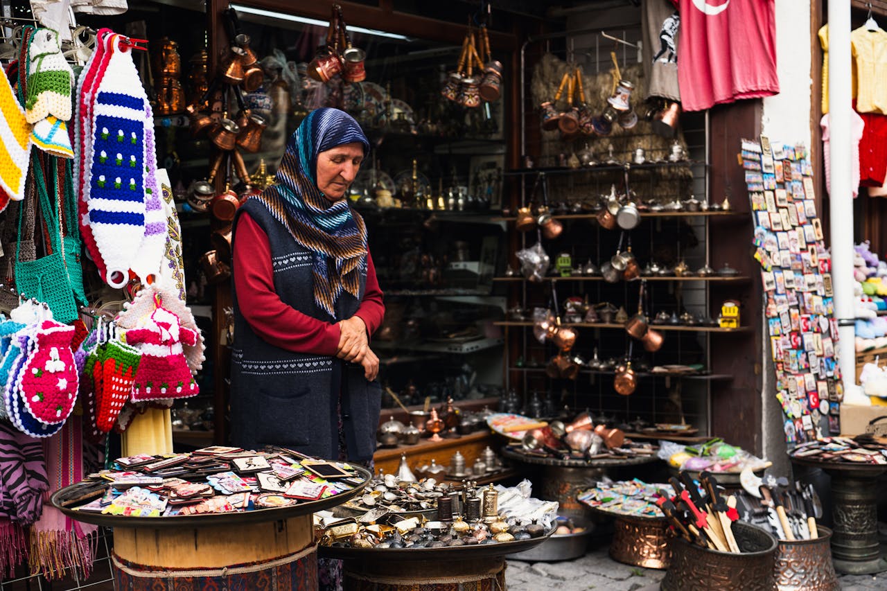 Elderly woman in hijab selling goods at a traditional Turkish bazaar.